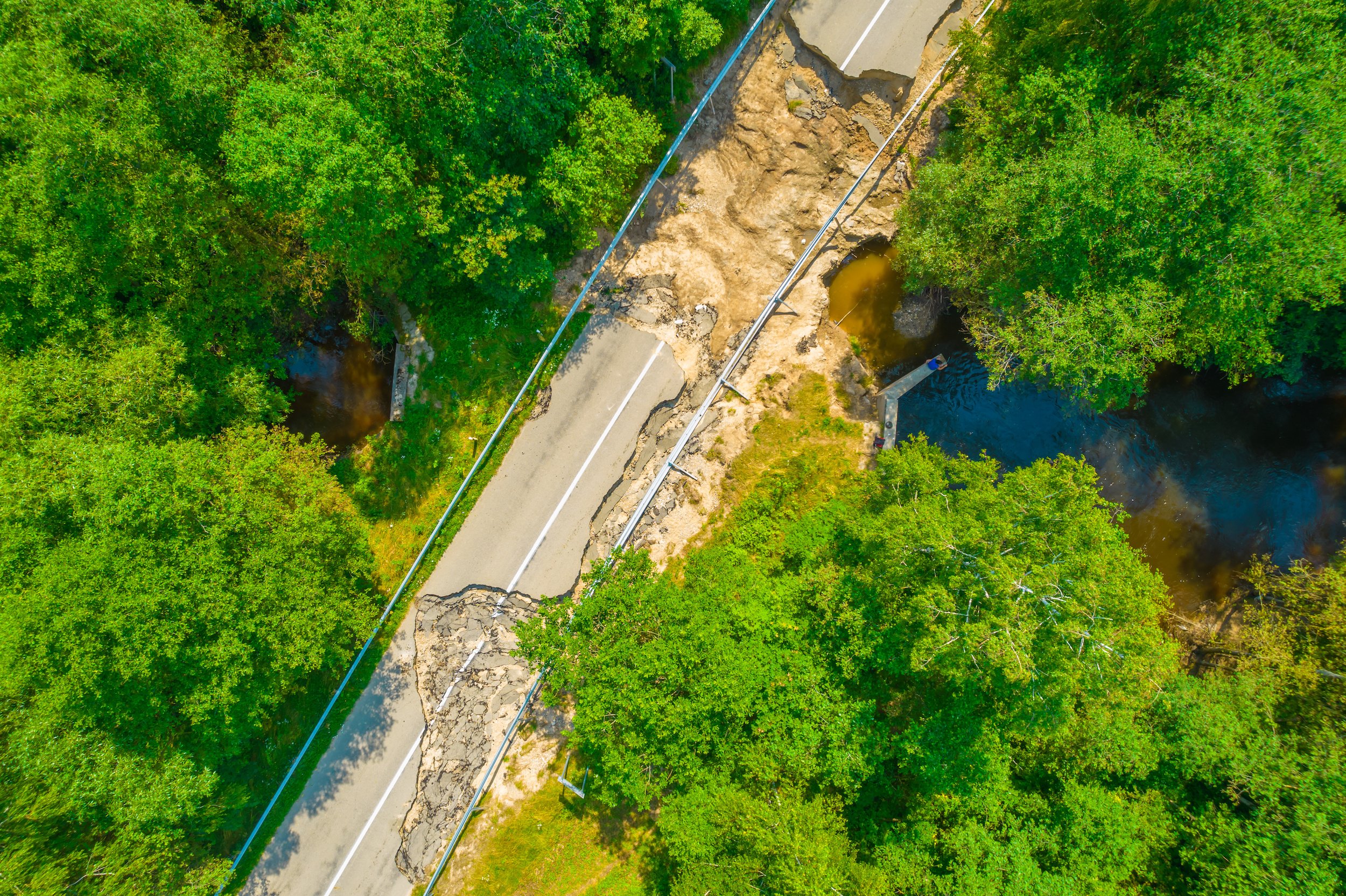 The asphalt road and bridge washed out and destroyed after the heavy rain and flood. Aerial photo